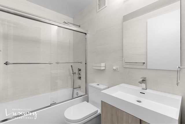 30 W 61st St Unit 24C, New York City, NY 10023 - full bathroom featuring combined bath / shower with glass door, tile walls, toilet, vanity, and visible vents