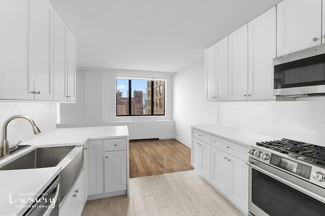 30 W 61st St Unit 24C, New York City, NY 10023 - kitchen with white cabinetry, light wood-style flooring, a sink, appliances with stainless steel finishes, and light countertops