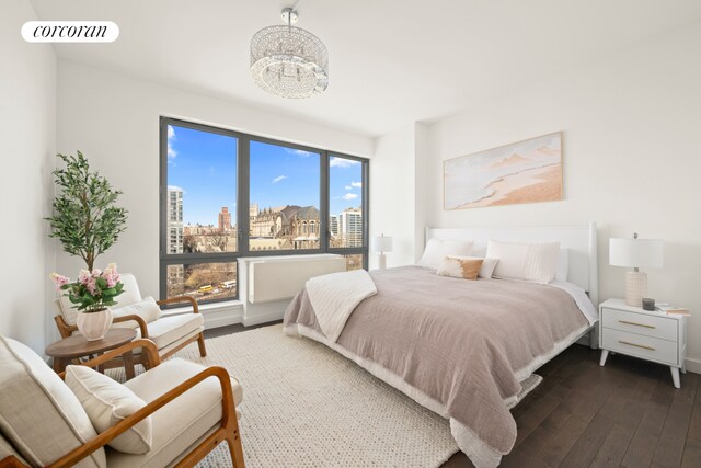 321 W 110th St Unit 12B, New York City, NY 10026 - bedroom with dark wood-style flooring, a chandelier, and a city view
