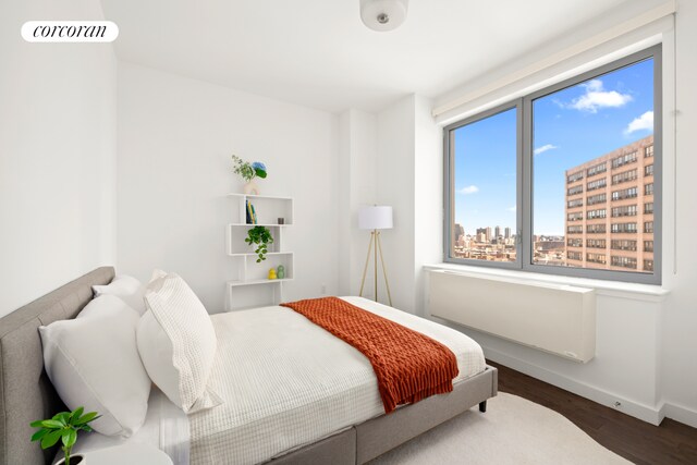 321 W 110th St Unit 12B, New York City, NY 10026 - bedroom featuring wood finished floors, baseboards, a city view, and radiator