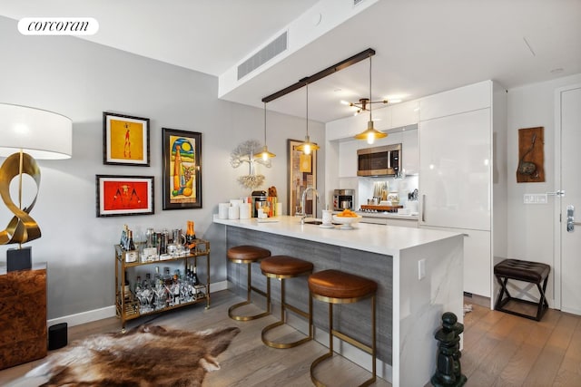 505 W 43rd St Unit 6K, New York City, NY 10036 - kitchen with stainless steel microwave, modern cabinets, white cabinets, and dark wood-style floors