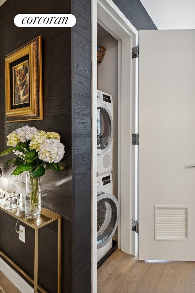 505 W 43rd St Unit 6K, New York City, NY 10036 - washroom with stacked washing machine and dryer and wood finished floors