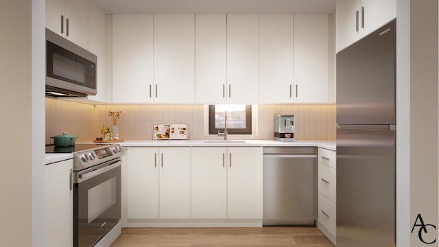 kitchen featuring tasteful backsplash, light countertops, white cabinetry, light wood-style floors, and appliances with stainless steel finishes