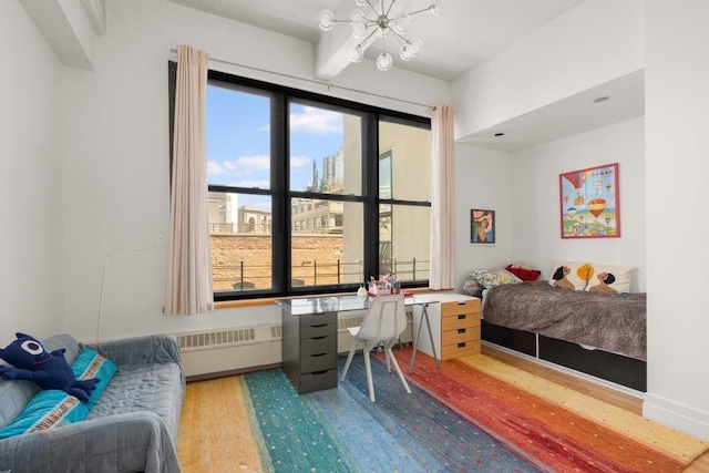 1 Main St Unit 7H, New York City, NY 11201 - bedroom featuring wood finished floors, radiator heating unit, a notable chandelier, and baseboards