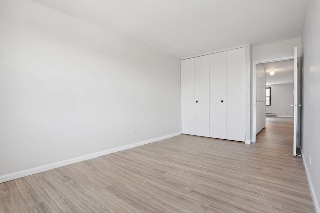 379 W St Unit 2B, New York City, NY 10014 - unfurnished bedroom with light wood-style flooring, a closet, baseboards, and a baseboard radiator
