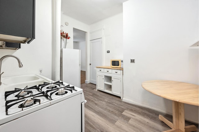 kitchen with white appliances, light wood-type flooring, white cabinetry, and light countertops