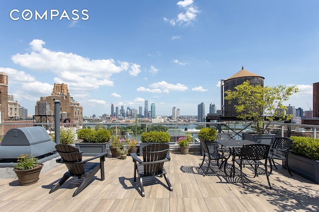 wooden terrace featuring a view of skyline and a grill