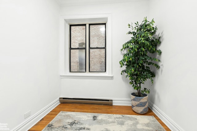 spare room with baseboards, a baseboard radiator, and wood finished floors