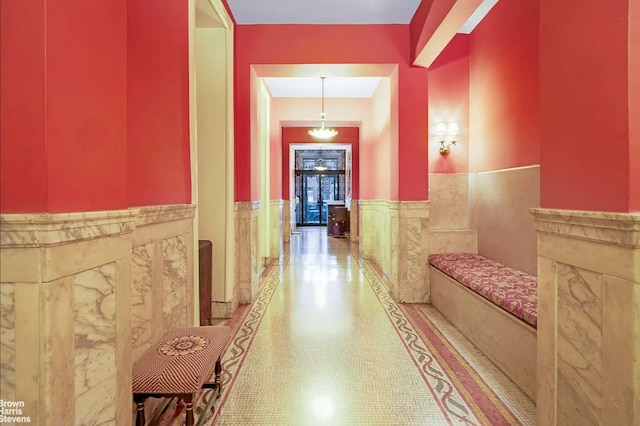 hall featuring tile walls and wainscoting