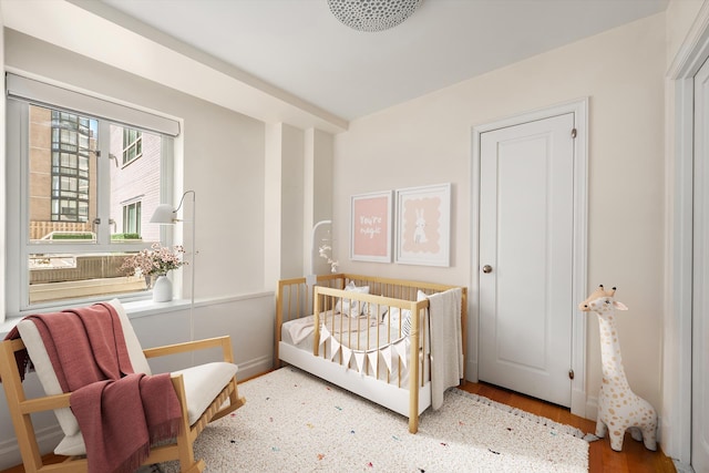 bedroom featuring wood finished floors and a nursery area