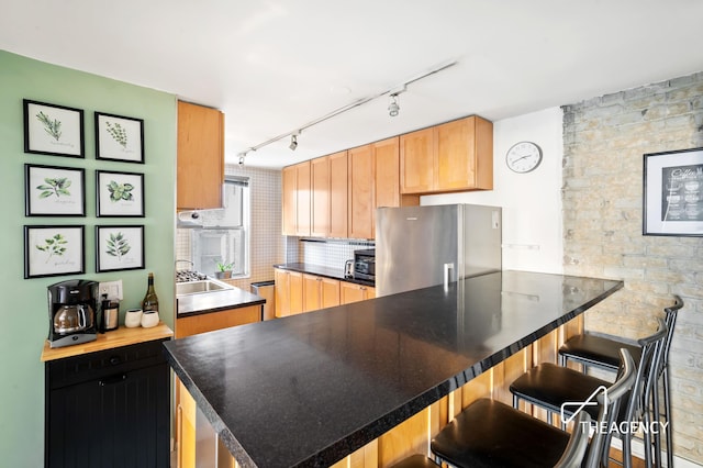 153 Bennett Ave Unit 3G, New York City, NY 10040 - kitchen with freestanding refrigerator, a kitchen bar, track lighting, a sink, and backsplash