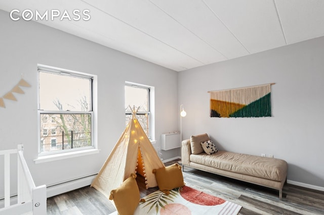 sitting room featuring a baseboard radiator, plenty of natural light, and wood finished floors