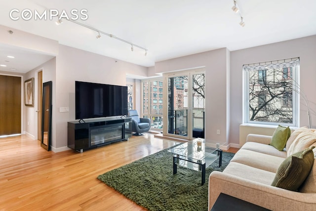 454 W 54th St Unit 3D, New York City, NY 10019 - living room featuring track lighting, light wood-style floors, and baseboards