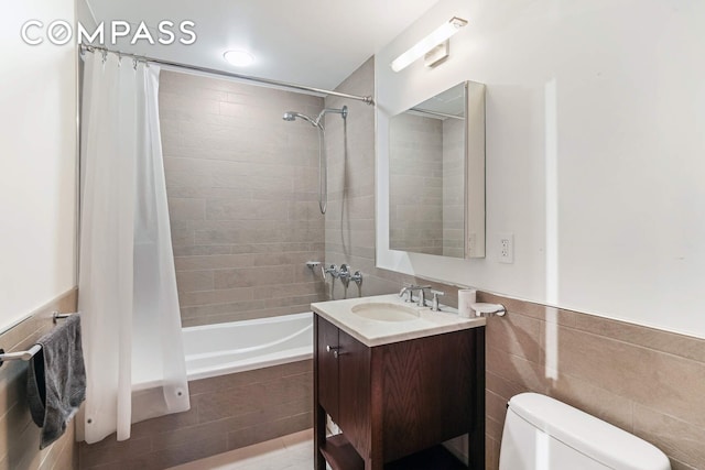 454 W 54th St Unit 3D, New York City, NY 10019 - bathroom with tiled shower / bath combo, toilet, vanity, tile walls, and wainscoting