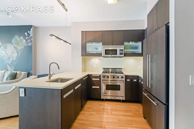 454 W 54th St Unit 3D, New York City, NY 10019 - kitchen with high quality appliances, a sink, a peninsula, and light wood finished floors