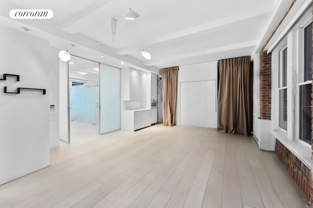 67 Park Ave Unit 1A, New York City, NY 10016 - unfurnished room featuring beamed ceiling, light wood-type flooring, brick wall, and recessed lighting
