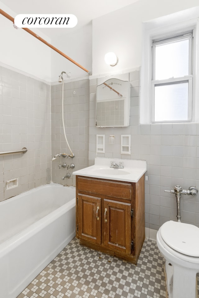 full bath with bathing tub / shower combination, tile walls, toilet, and vanity