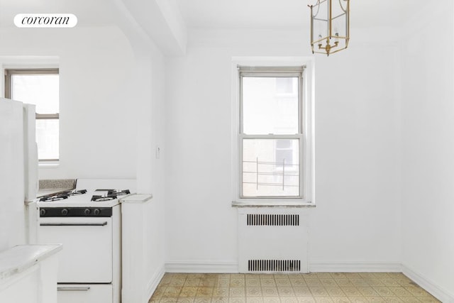 kitchen with radiator heating unit, white appliances, light countertops, light floors, and baseboards
