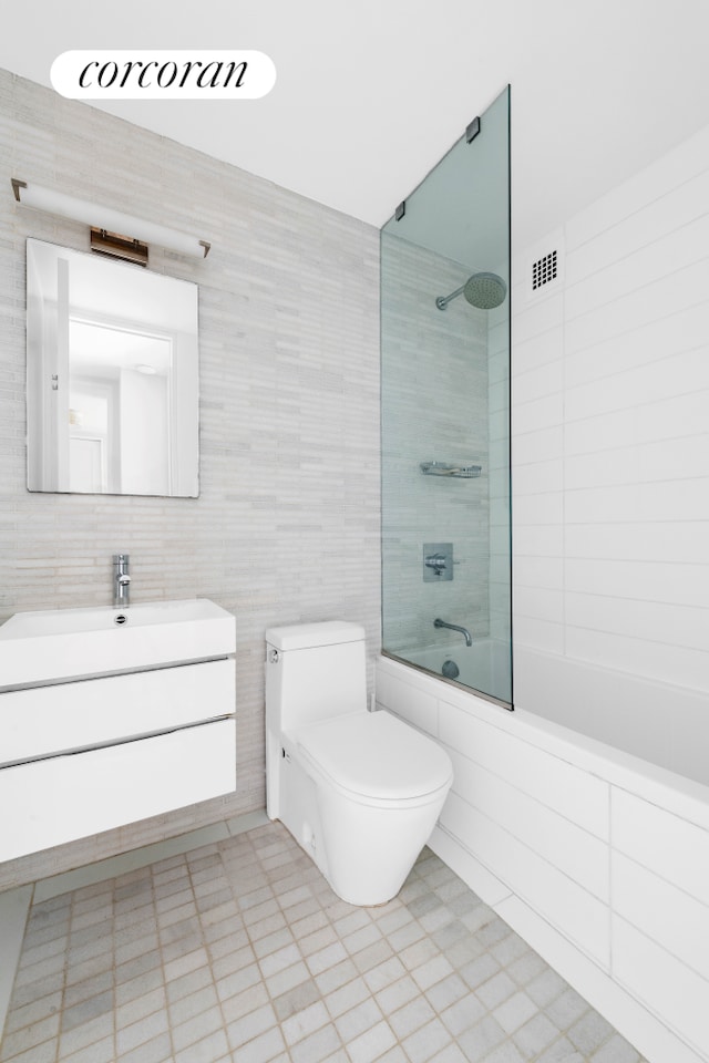 bathroom featuring tile walls, vanity, shower / bathtub combination, toilet, and visible vents