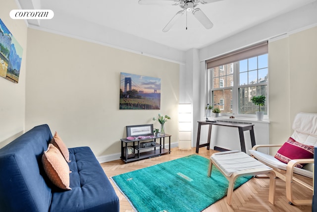 living area with baseboards and a ceiling fan