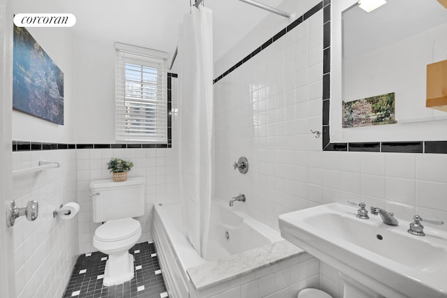 bathroom featuring toilet, tile walls, tile patterned floors, a sink, and shower / tub combo
