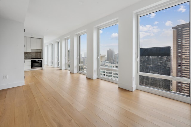 15 W 61st St Unit 27C, New York City, NY 10023 - unfurnished living room featuring a city view, light wood-type flooring, and a fireplace
