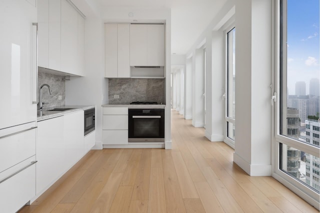 15 W 61st St Unit 27C, New York City, NY 10023 - kitchen with wall oven, modern cabinets, white cabinets, black microwave, and backsplash