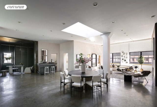 dining room with a skylight, recessed lighting, finished concrete floors, and a towering ceiling
