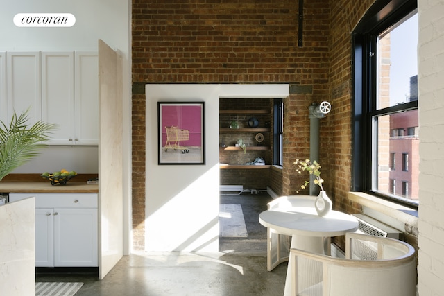 interior space with finished concrete flooring and brick wall