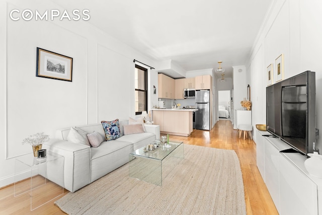 living room with light wood-style floors and ornamental molding