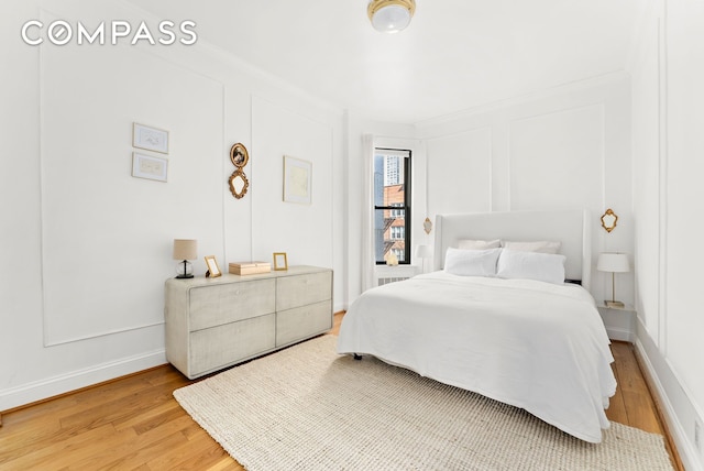 bedroom with light wood-type flooring, baseboards, and ornamental molding