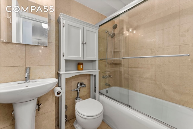 bathroom with tile walls, enclosed tub / shower combo, and toilet