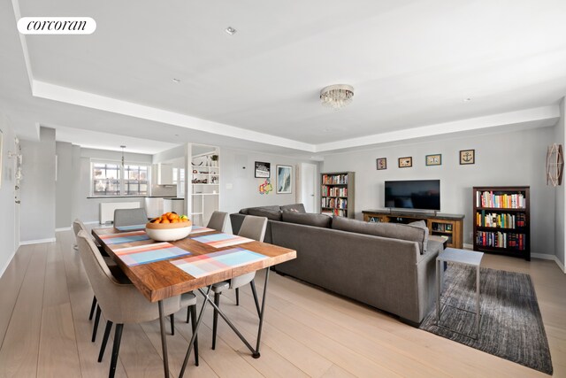 345 E 56th St Unit 21F, New York City, NY 10022 - dining room with a tray ceiling, light wood-style floors, and baseboards