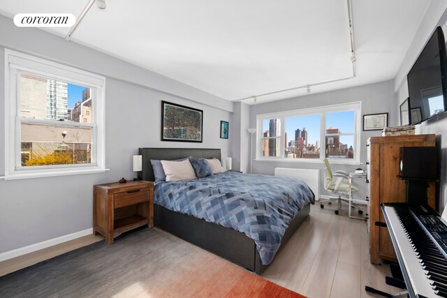 345 E 56th St Unit 21F, New York City, NY 10022 - bedroom featuring rail lighting, light wood-type flooring, and baseboards