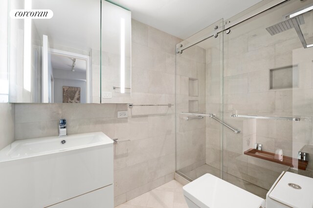 345 E 56th St Unit 21F, New York City, NY 10022 - bathroom featuring tile walls, a stall shower, vanity, and toilet