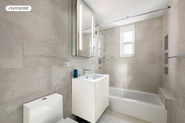 345 E 56th St Unit 21F, New York City, NY 10022 - bathroom with vanity, toilet, shower / bath combination, tile walls, and tile patterned flooring