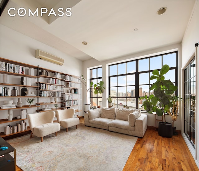 living area with recessed lighting, a wall mounted AC, and wood finished floors