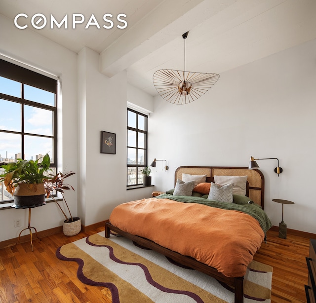bedroom featuring baseboards, multiple windows, and wood finished floors