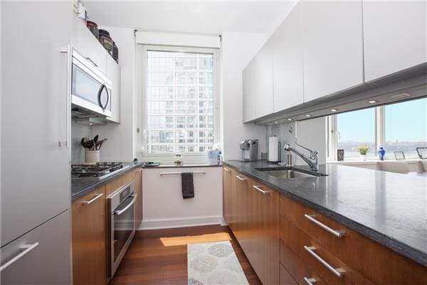 100 Riverside Blvd Unit 23-D, New York City, NY 10069 - kitchen with stainless steel appliances, dark wood-style flooring, healthy amount of natural light, and white cabinetry
