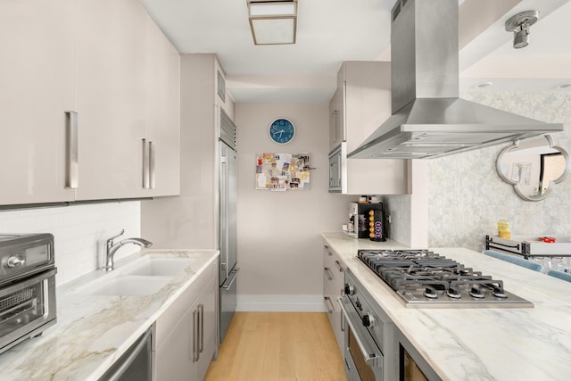 211 Madison Ave Unit 5B, New York City, NY 10016 - kitchen featuring island range hood, a sink, built in appliances, baseboards, and decorative backsplash