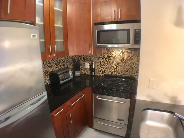 kitchen with stainless steel appliances, a sink, glass insert cabinets, and tasteful backsplash