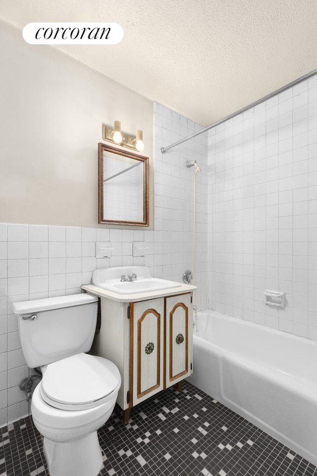 bathroom with tile walls, toilet, shower / tub combination, tile patterned floors, and a textured ceiling