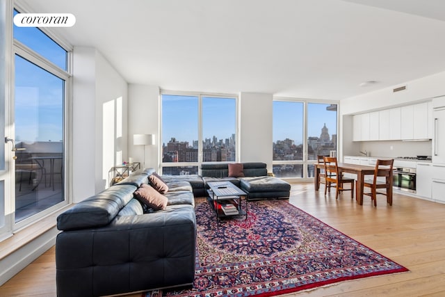 340 E 23rd St Unit Ph3D, New York City, NY 10010 - living area with light wood-style floors, a view of skyline, and a wall of windows
