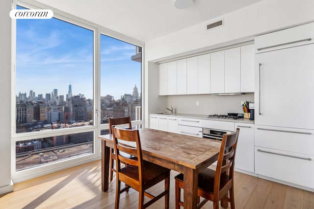 340 E 23rd St Unit Ph3D, New York City, NY 10010 - dining area featuring light wood-style floors, a view of skyline, and a wall of windows