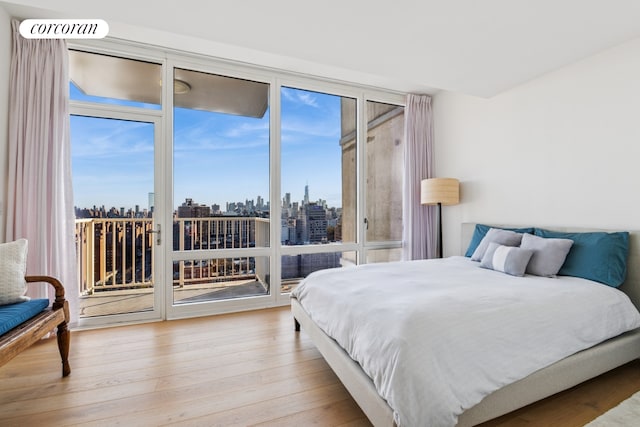 340 E 23rd St Unit Ph3D, New York City, NY 10010 - bedroom featuring access to outside, a view of skyline, and wood finished floors