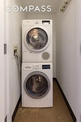 laundry area featuring laundry area, baseboards, and stacked washer and clothes dryer