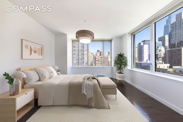 bedroom featuring dark wood-type flooring, a city view, baseboards, and multiple windows