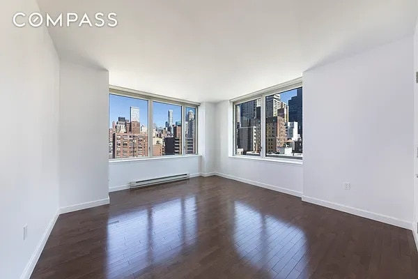 spare room with a view of city, baseboards, baseboard heating, and wood-type flooring