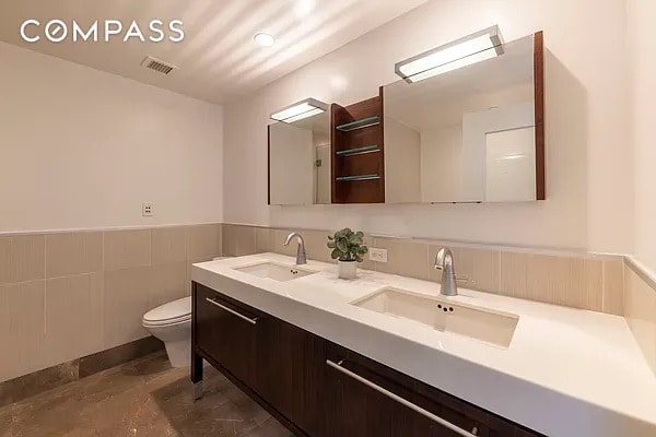 bathroom featuring a sink, toilet, double vanity, and visible vents