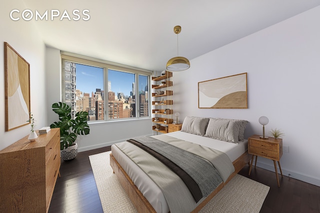 bedroom with baseboards, a view of city, and hardwood / wood-style floors